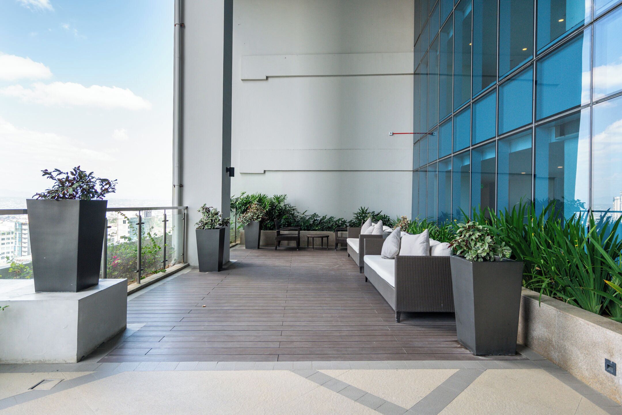 A rooftop terrace with a seating area, potted plants, and a view of the cityscape.