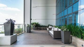 A rooftop terrace with a seating area, potted plants, and a view of the cityscape.