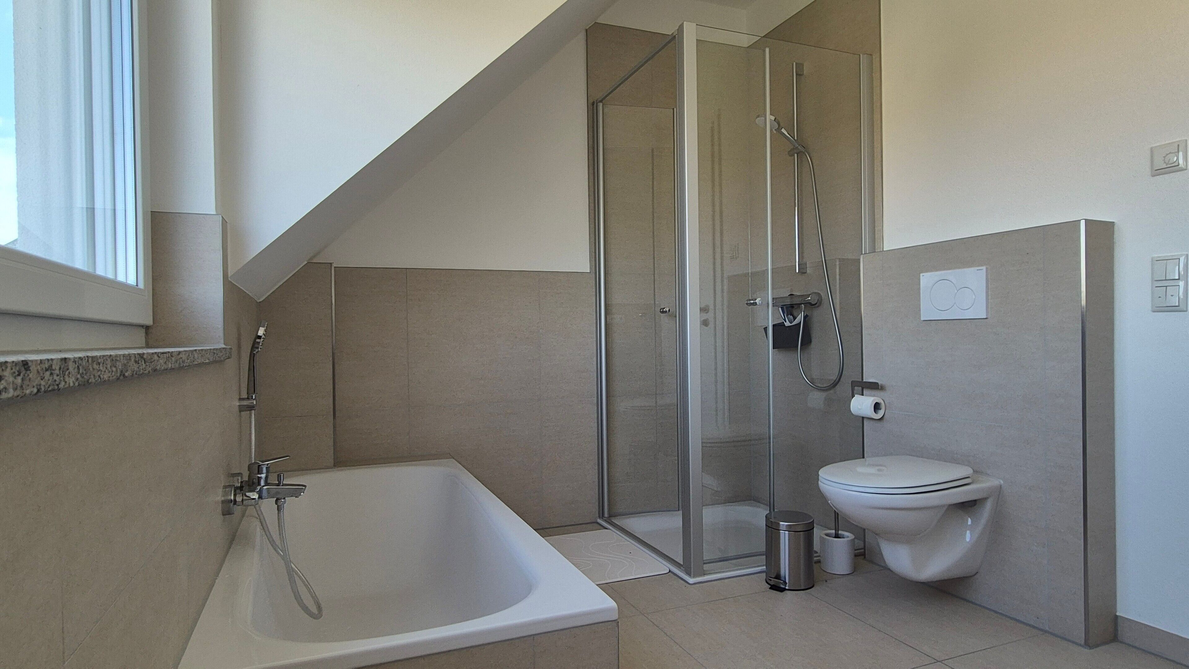 Ein modernes Badezimmer mit Badewanne, Toilette und einer Duschkabine.