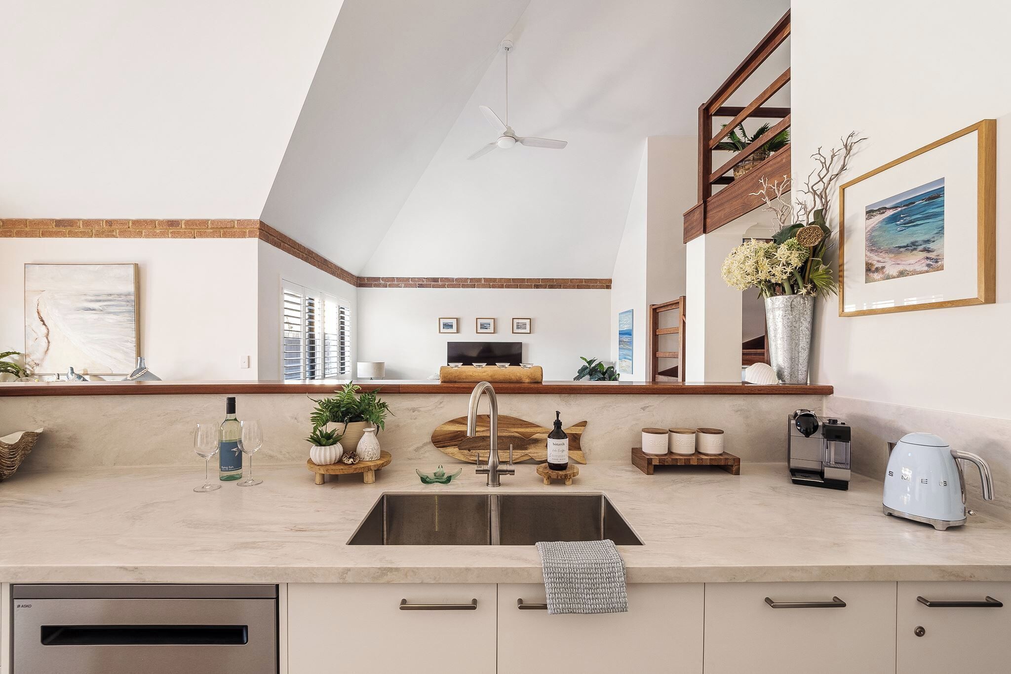 A modern kitchen with a built-in sink, a coffee machine, and a hanging ceiling fan.