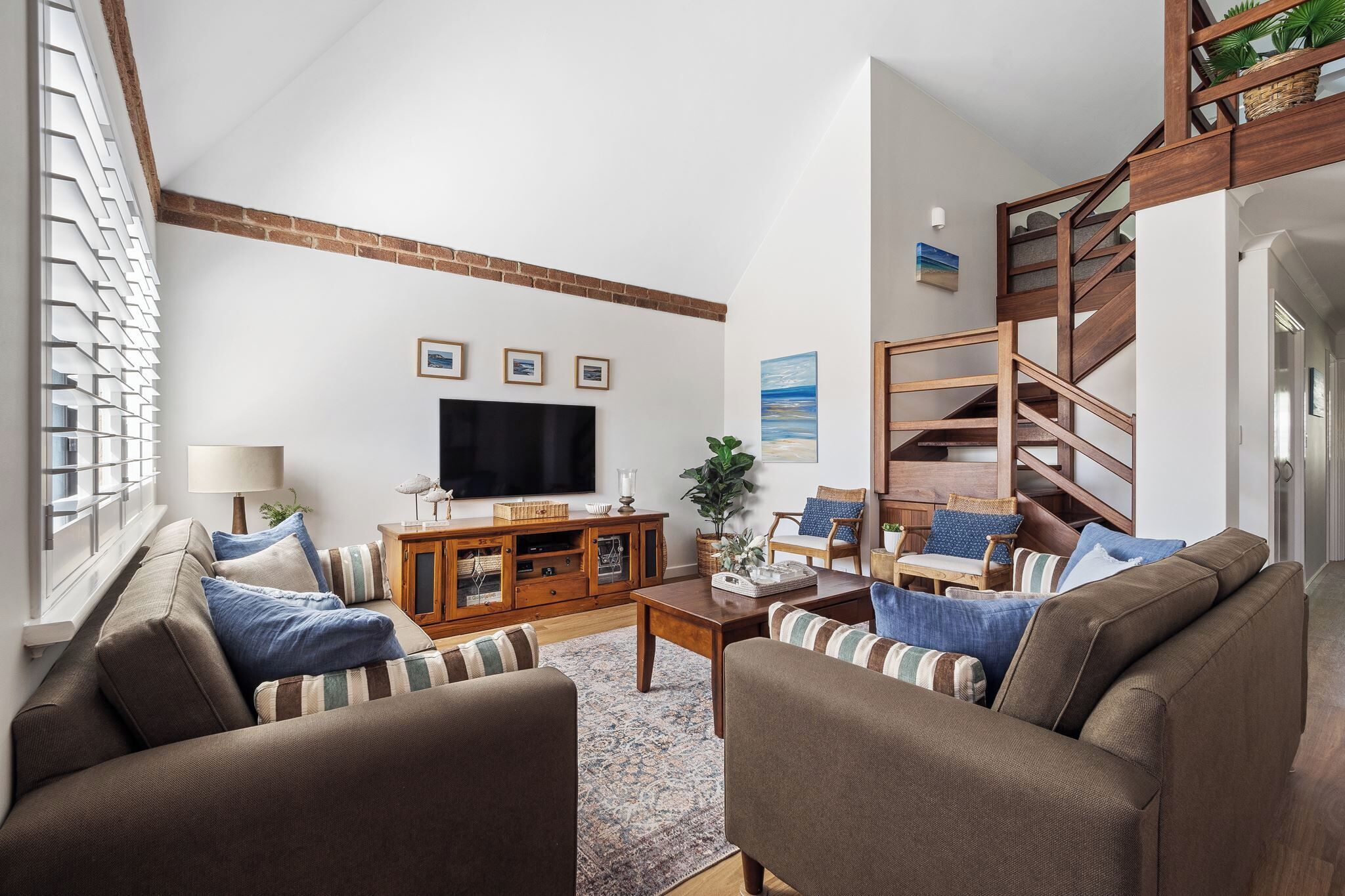 Una sala de estar con chimenea, televisión y escalera.