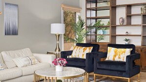 A living room with a sofa, two armchairs, a coffee table, a lamp, and a bookshelf. - 4500SF Dream Home｜Close to Disney｜Skyline View (Santa Ana)