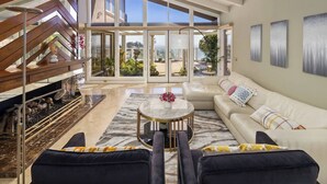 A spacious living area with a high ceiling, a modern staircase, and a large glass door leading to an outdoor view. - 4500SF Dream Home｜Close to Disney｜Skyline View (Santa Ana)
