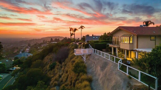A residential area with a house featuring a balcony, a view of the city, and a sunset in the background. - 4500SF Dream Home｜Close to Disney｜Skyline View (Santa Ana)