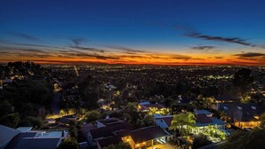 A cityscape at dusk with illuminated buildings and a sunset. - 4500SF Dream Home｜Close to Disney｜Skyline View (Santa Ana)