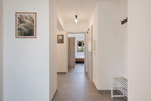 A hallway with a bed, a radiator, and a door leading to a room.