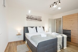Une chambre à coucher moderne avec un lit, des lampes de chevet, un plancher en bois et un tableau accroché au mur.