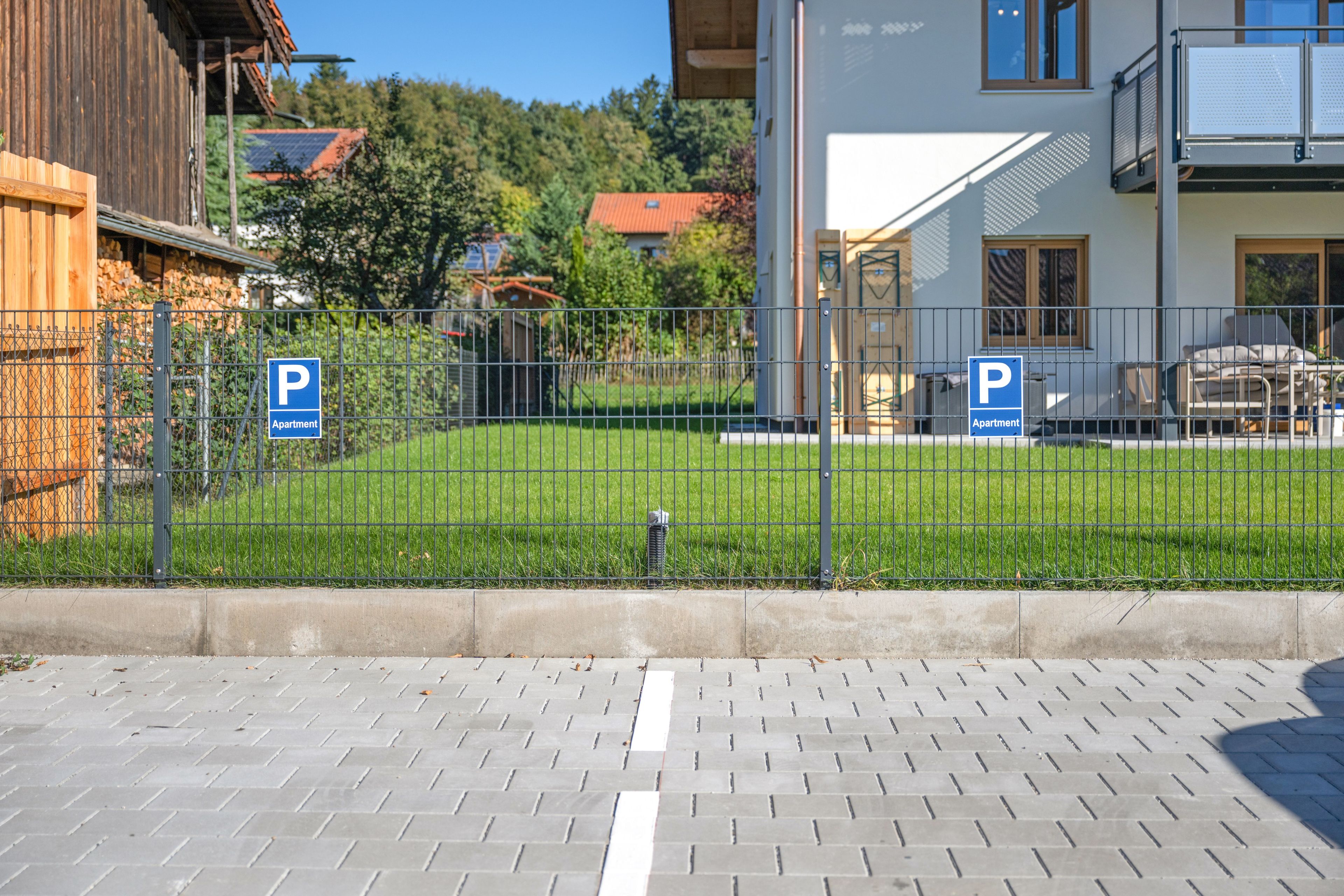 A fenced outdoor area with two blue parking signs indicating apartment parking.