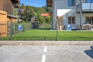 Un espace extérieur clôturé, agrémenté de deux panneaux de signalisation bleus indiquant les places de stationnement réservées aux résidents de l’immeuble.