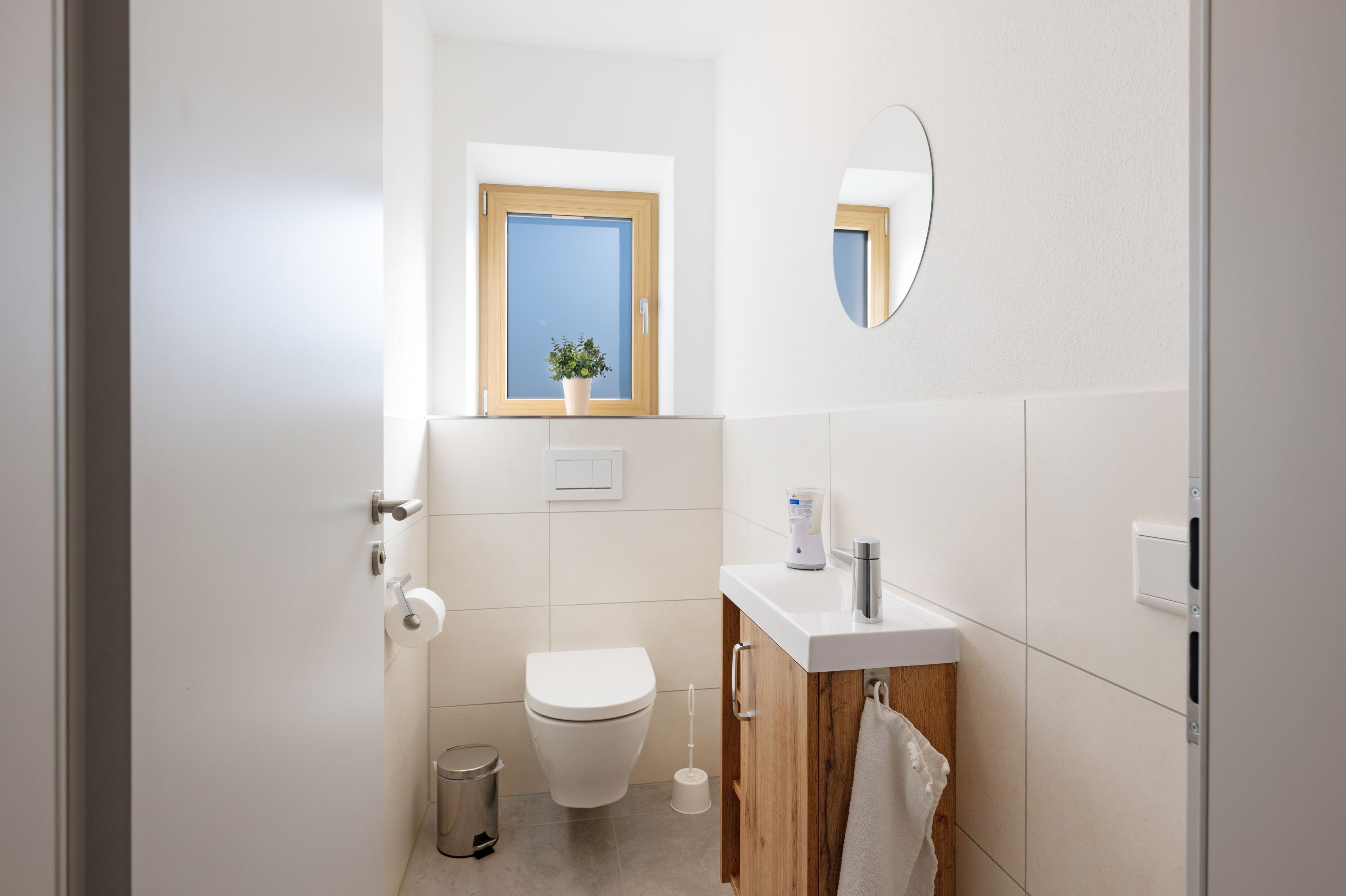 Un bagno moderno con il water, un lavandino e una piccola finestra con una pianta.