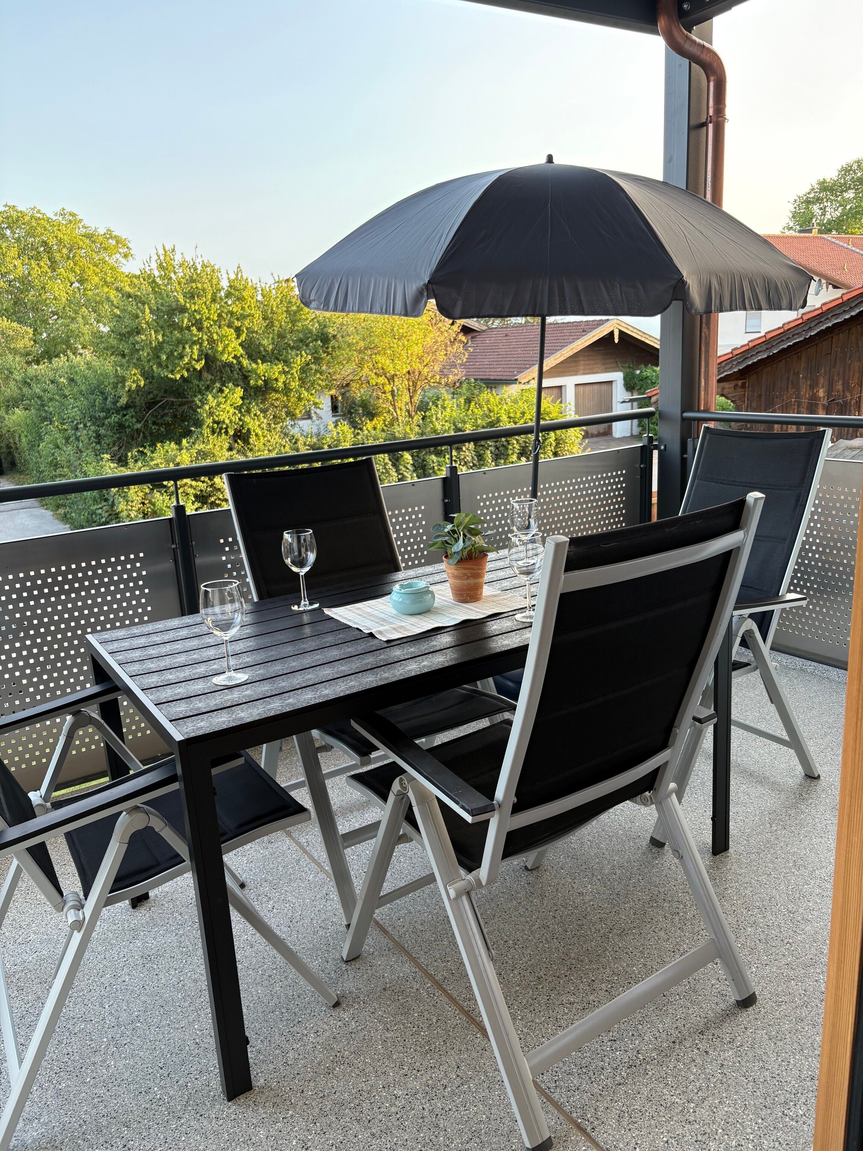 An outdoor patio with a table, chairs, and an umbrella.