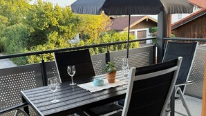 Ulkoterassi, jossa on pöytä, tuoleja ja aurinkovarjo.