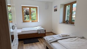 Makuuhuoneessa on kaksi sänkyä, puulattia, ikkuna, josta on näkymä, ja kattovalaisin.