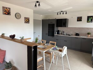 A modern kitchen with grey cabinets, a wooden countertop, and a dining area with a white table and chairs.