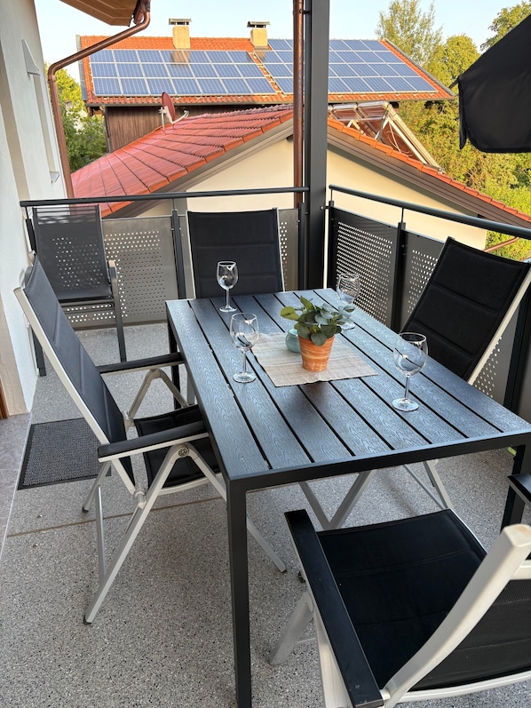 An outdoor patio with a table and chairs, a potted plant, and solar panels on the roof.