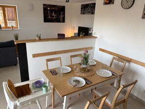 A dining area with a wooden table set for four, surrounded by chairs.