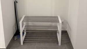 A room with a white bench, a broom, and two wall-mounted hooks.