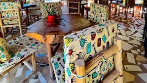 A restaurant with thatched roof, colorful patterned furniture, and a tiled floor. - Kili Palladium Homes Apartments - Soweto (Moshi)