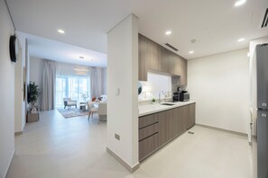 A modern kitchen with wooden cabinets, a built-in oven, and a refrigerator. - Bloomfields 1BR in Fairways 1 - Yas (Abu Dhabi)