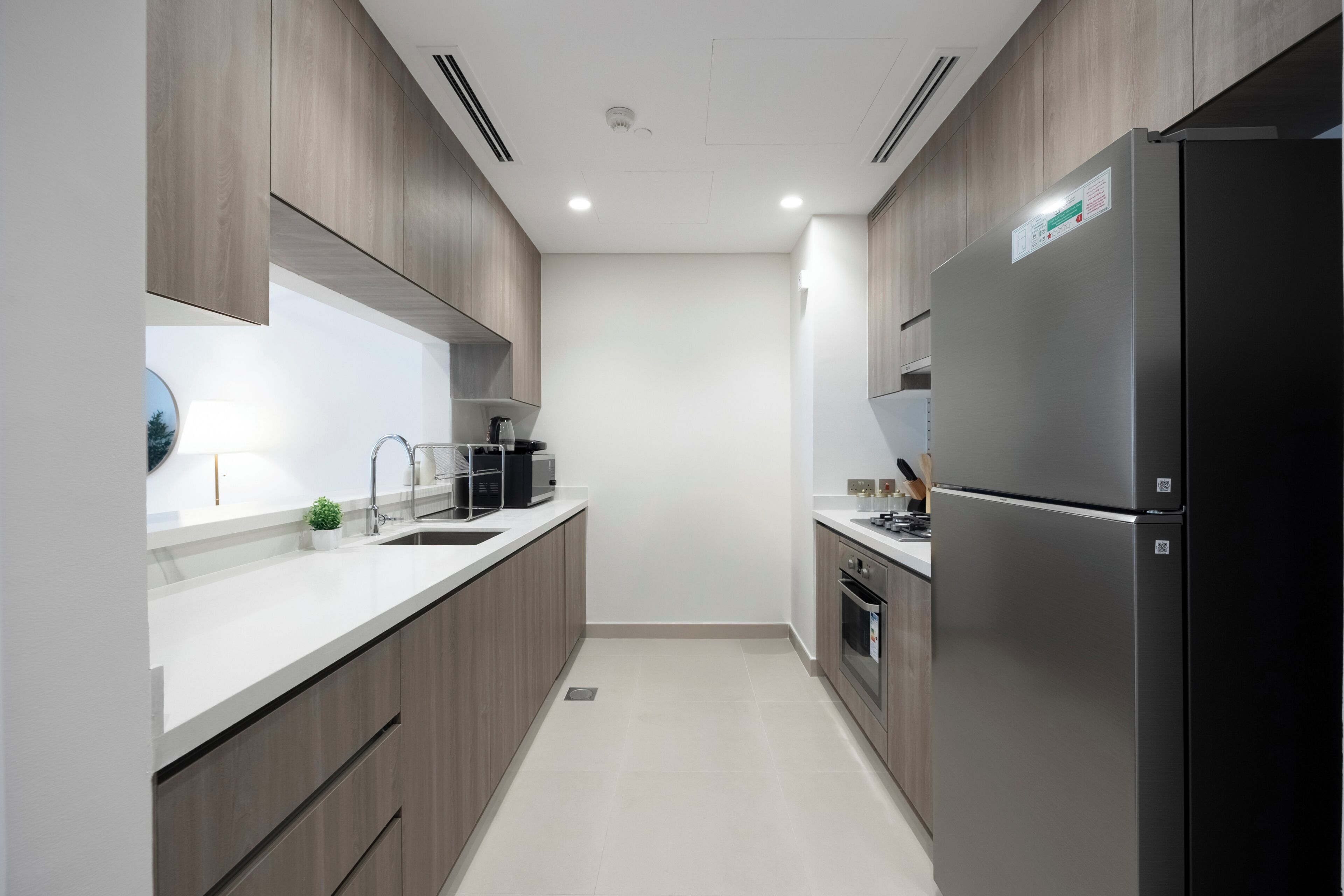 A modern kitchen with wooden cabinets, a stainless steel refrigerator, and a built-in oven.