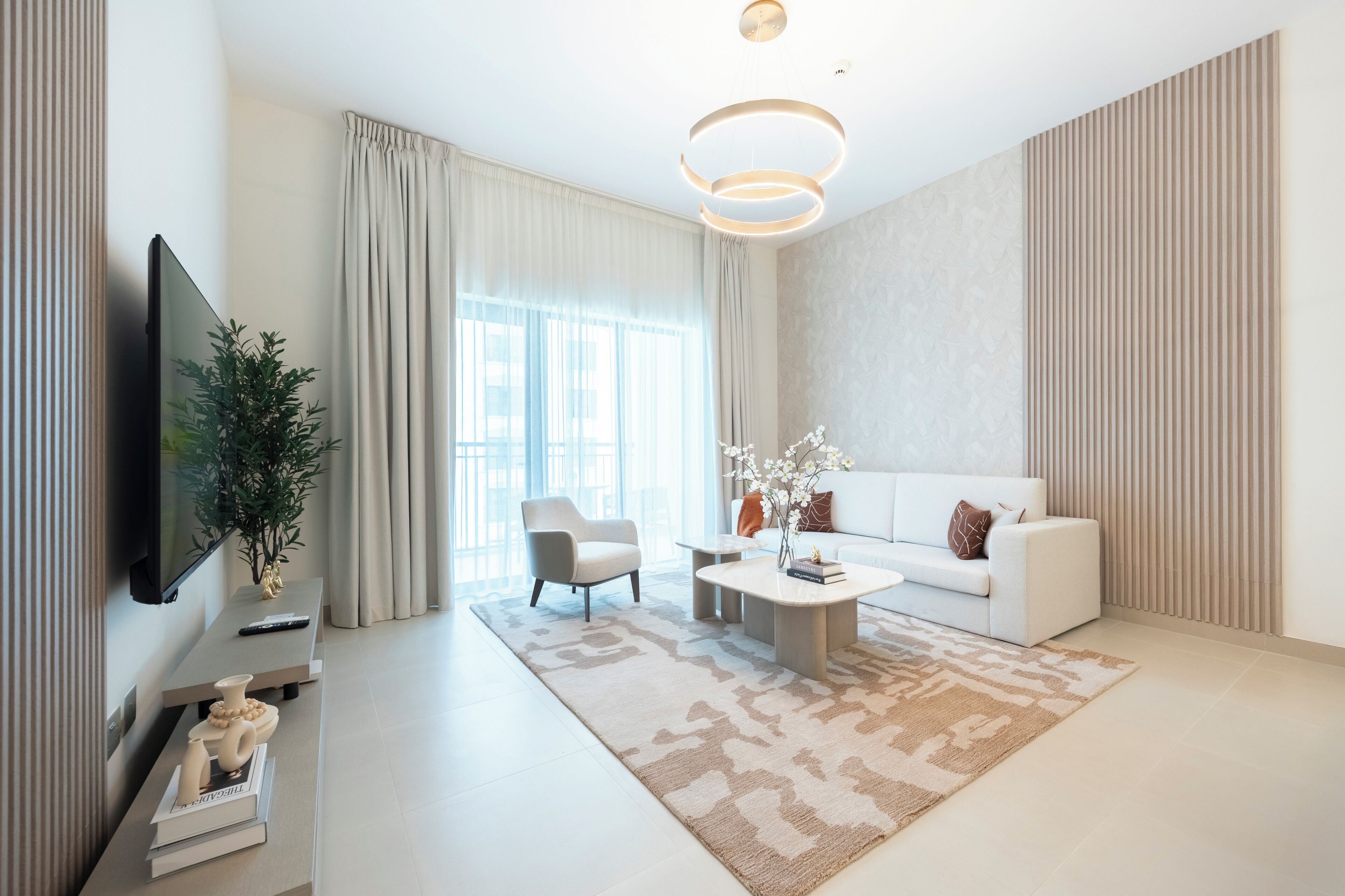 A modern living room with a flat-screen TV, a sofa, a coffee table, and a decorative plant.