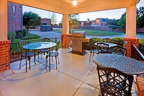 Eine Terrasse im Freien mit Grill, Tischen und Stühlen.