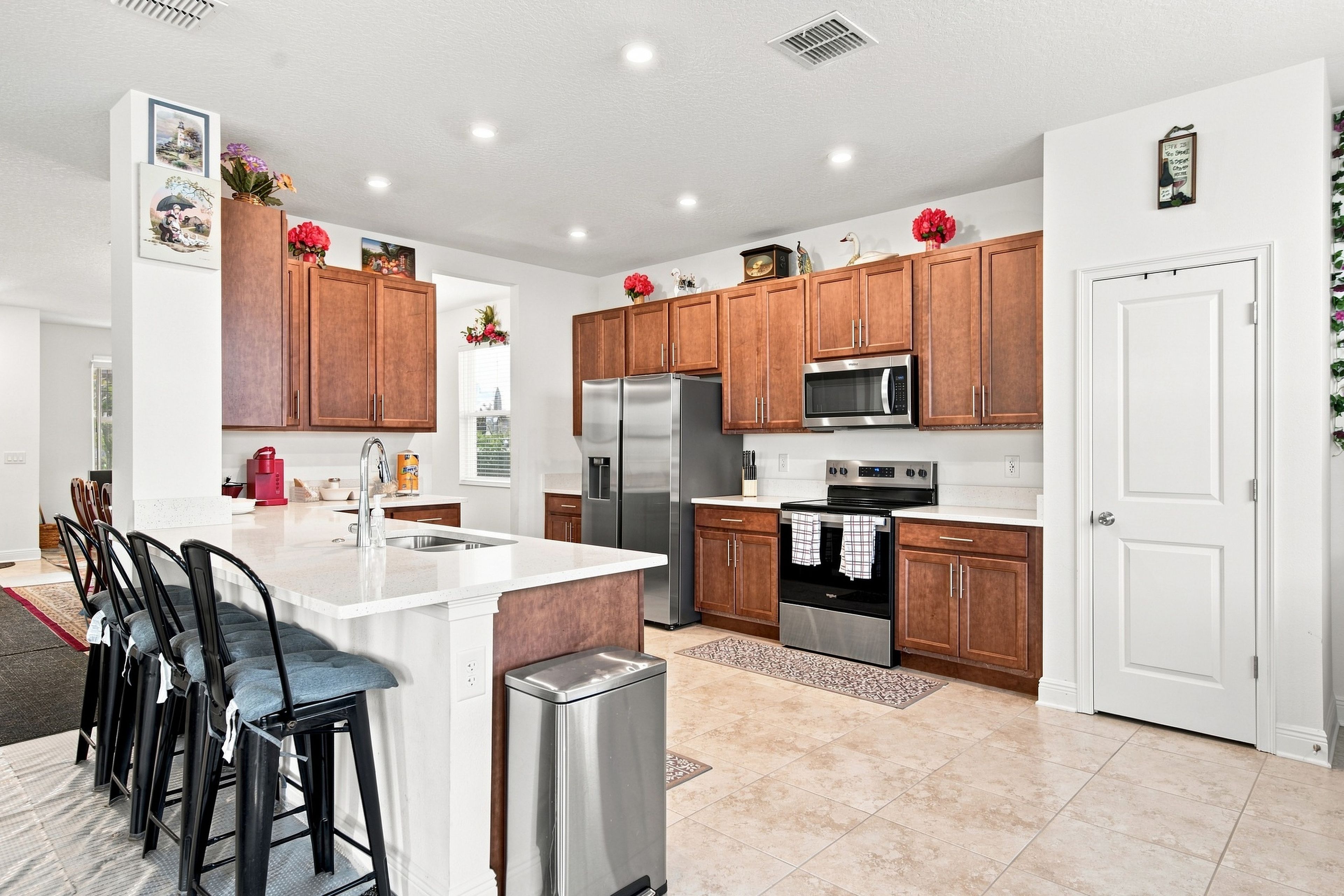 A modern kitchen with a central island, stainless steel appliances, and wooden cabinets.
