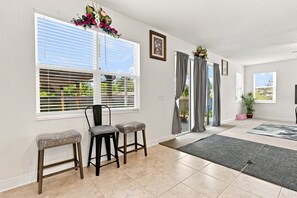 A spacious living area with a dining set, large windows, and a view of the outdoors. - 5BR w/ Pool Table & Fire pit near Madeira Beach (Pinellas Park)