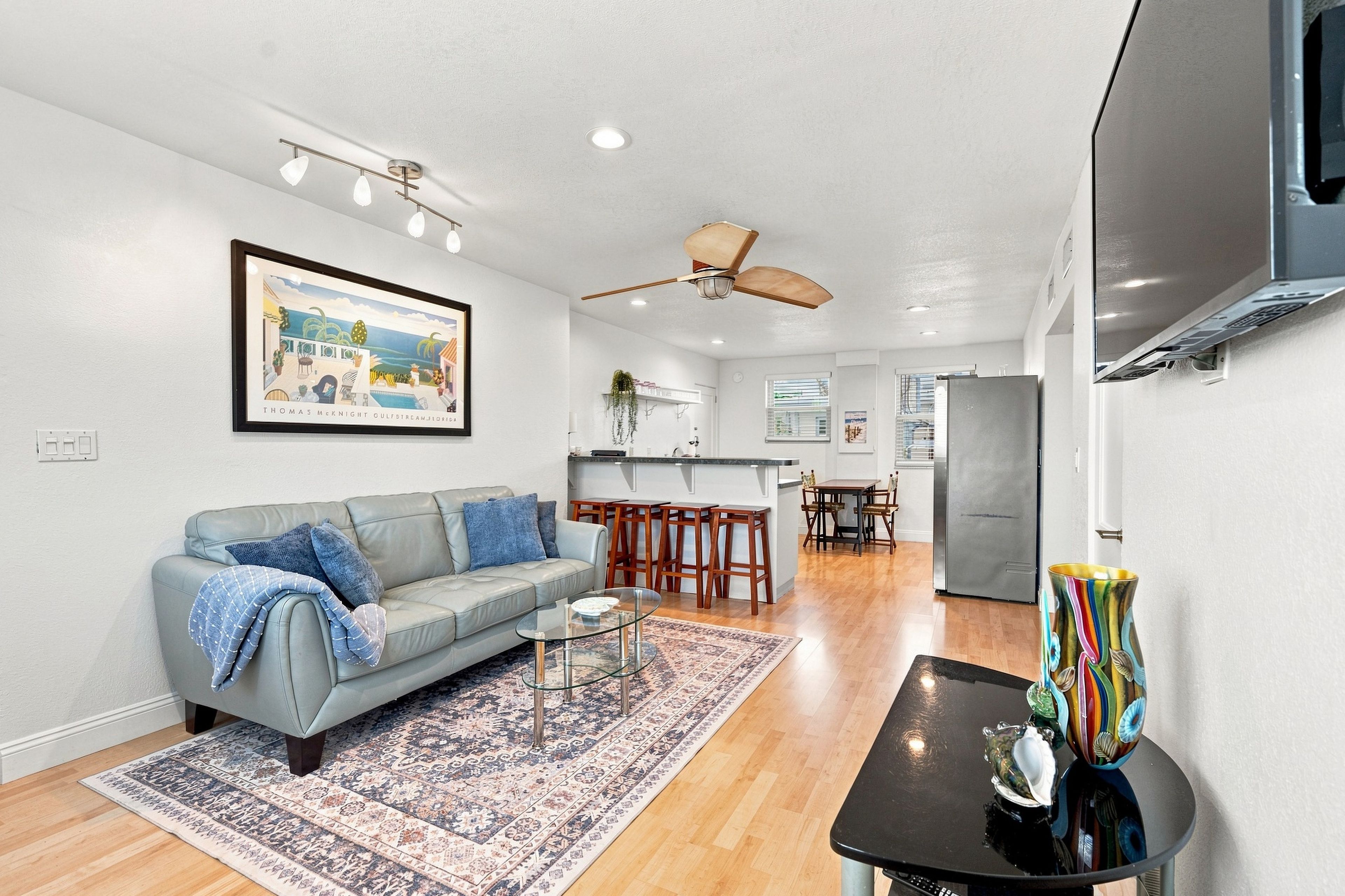 A modern living room with a grey sofa, a glass coffee table, and a patterned rug.