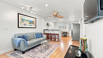 A modern living room with a grey sofa, a glass coffee table, and a patterned rug.