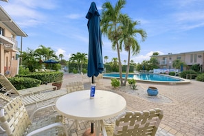 Zona junto a la piscina con mesa y sillas, una sombrilla y una piscina.