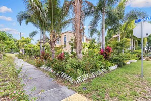 A residential area with a sidewalk, palm trees, and a house with a white fence. - 4BR w/ Pool Table & BBQ just 10 Mins to the Beach (Pinellas Park)