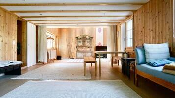 Ein geräumiger Raum mit Holzwänden und -decke, einer Couch, einem Tisch und einem Klavier.