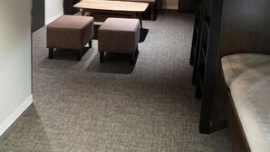 A compact hotel room with a bed, a sofa, a small table, and a TV. - ALPHABED INN Otaru Ekimae (Otaru)