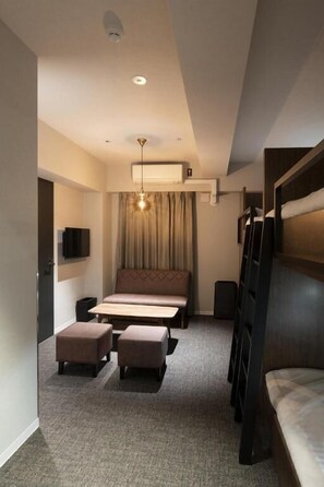 A compact hotel room with a bed, a sofa, a small table, and a TV. - ALPHABED INN Otaru Ekimae (Otaru-shi)