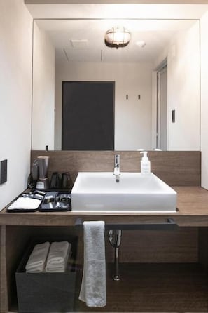 A modern bathroom with a large mirror, a white sink, and a towel rack. - ALPHABED INN Otaru Ekimae (Otaru-shi)