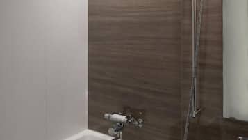 A bathroom with a bathtub, a shower, and a mirror.