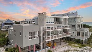 Um imóvel à beira-mar com vários andares, piscina, área de estar externa e vista para o oceano.
