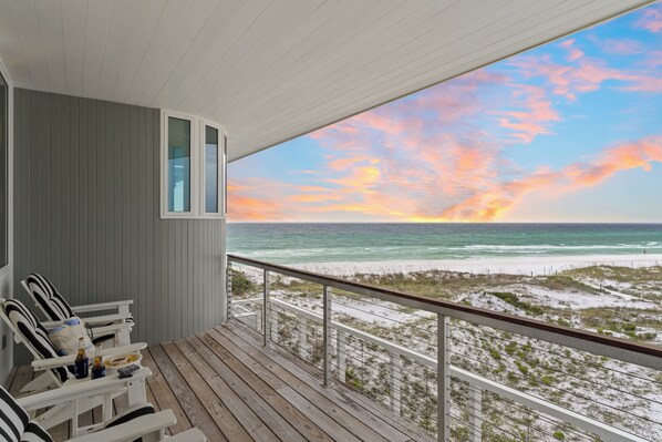 Une terrasse en bois offrant une vue sur la plage et l’océan.