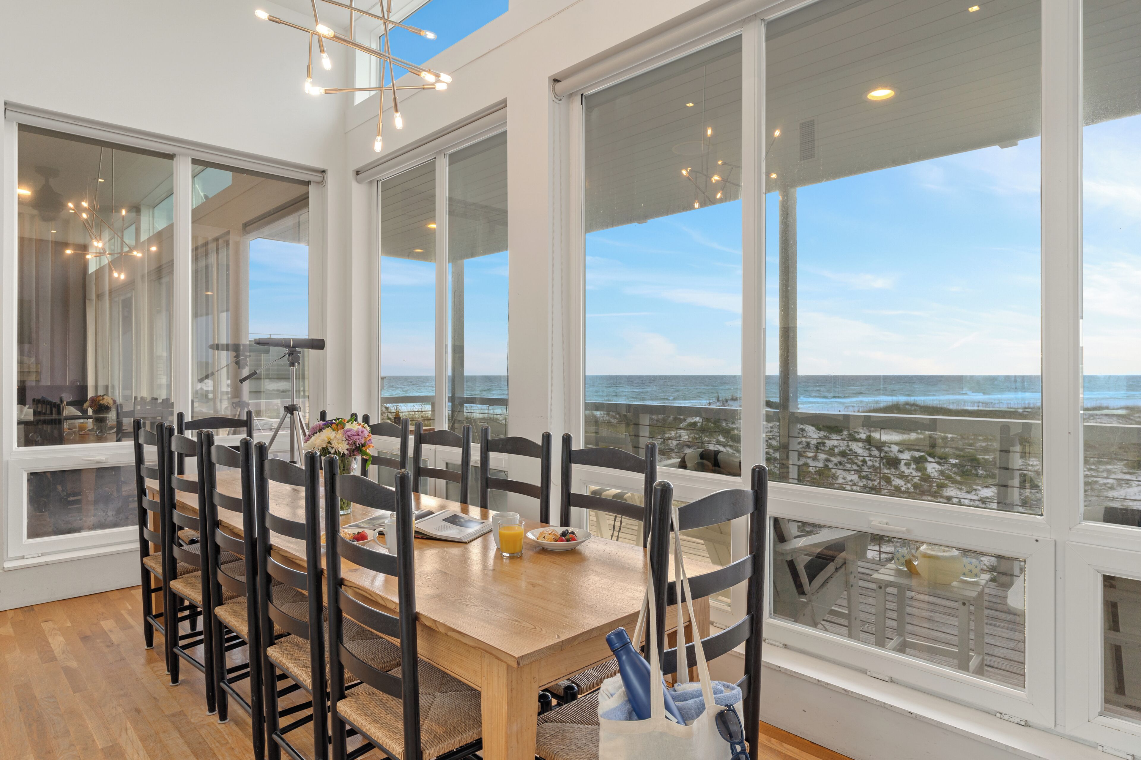 A dining area with a large table, chairs, and a view of the ocean.