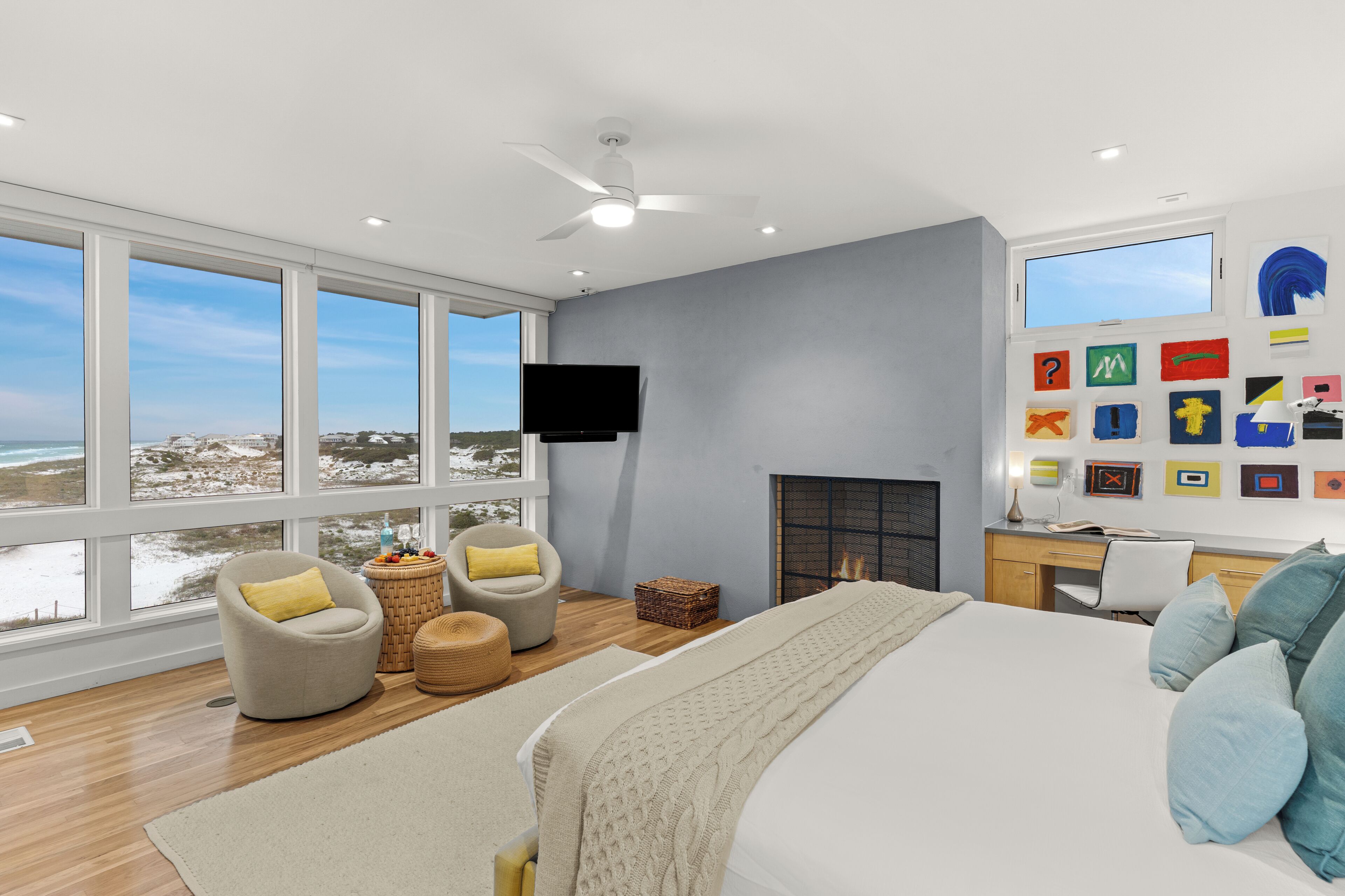 A modern bedroom with a large bed, a desk, and a television.