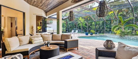 A poolside lounge with a sofa, a coffee table, and a fire feature.