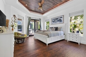 A bedroom with a large bed, a chair, a dresser, and a ceiling fan. - Screened Pool + Outdoor Kitchen + Fire Table | Beaches | A Peaceful Paradise (Naples)