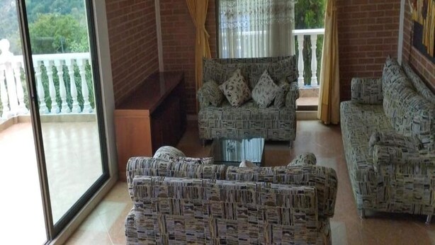 Habitación con balcón, muebles de mimbre y vista a zonas verdes.