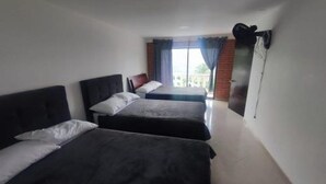 Une chambre d’hôtel avec deux lits, une grande fenêtre avec des rideaux et une vue sur l’extérieur.