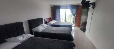 A hotel room with two beds, a large window with curtains, and a view of the outside.