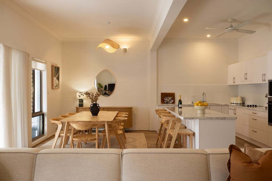 Een moderne keuken met witte kasten, een eethoek met houten meubels, en een plafondventilator.