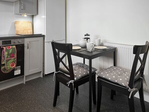 Une cuisine compacte avec un coin repas, comprenant un réfrigérateur, un four et une table mise avec des assiettes et une théière.