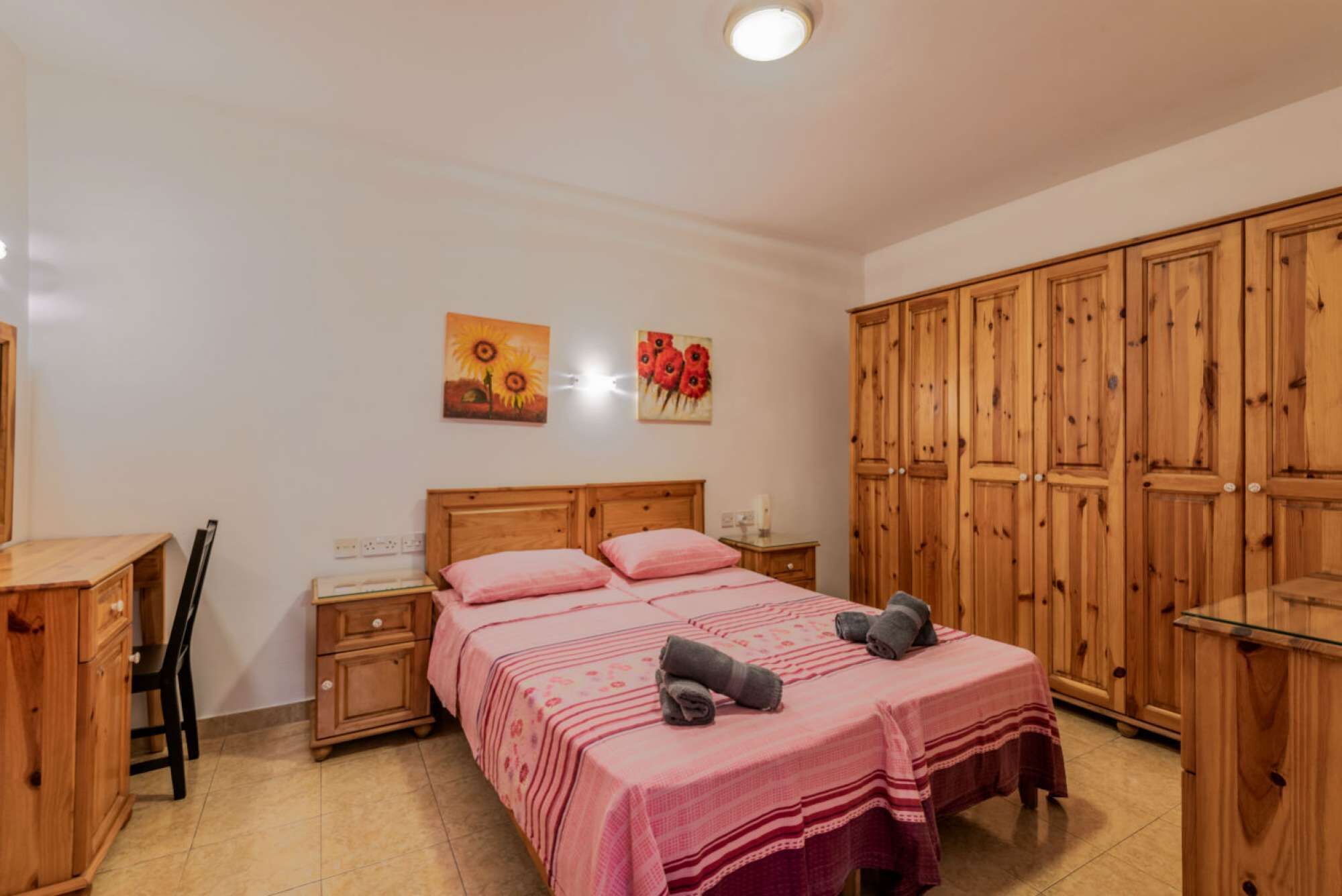 Ein Schlafzimmer mit einem Doppelbett, einem Holzschrank und zwei an der Wand befestigten Bildern.
