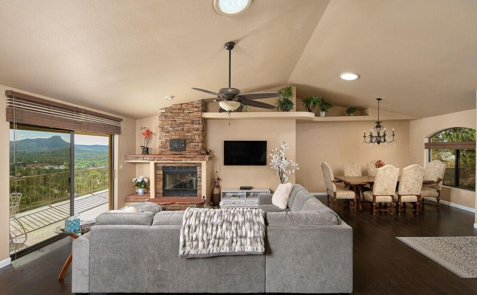 A spacious living room with a fireplace, a dining area with a chandelier, and a balcony with a view.